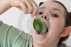 Little girl eating spinach. Concept of healthy food and vitamins. Selected focus. Close-up.