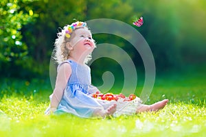Little girl eating strawberry watching a butterfly