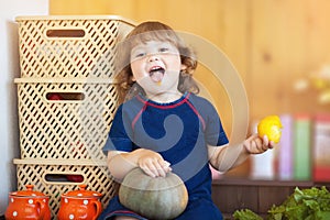 Little girl eating tomato in the kitchen