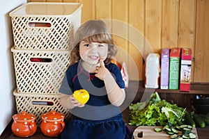 Little girl eating tomato in the kitchen
