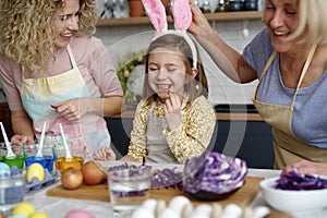 Little girl eating verdure during Easter with mother and grandmother