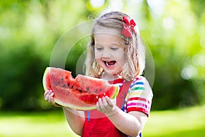 Little girl eating watermelon in the garden