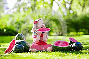 Little girl eating watermelon in the garden