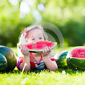 Little girl eating watermelon in the garden