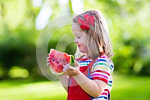 Little girl eating watermelon in the garden