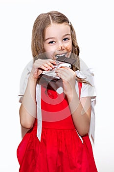 Little girl eats a bar of chocolate on a white background