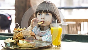 Little girl eats in a fast food cafe