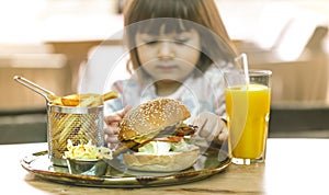 Little girl eats in a fast food cafe