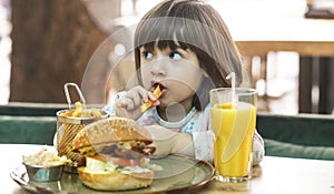 Little girl eats in a fast food cafe