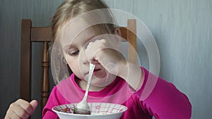 Little girl eats soup at home in kitchen