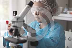 Little girl at an elementary school, using microscope research, testing in science class. Toddler girl doing