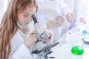 Little girl at an elementary school, using microscope research, testing in science class. Toddler girl doing biochemistry research