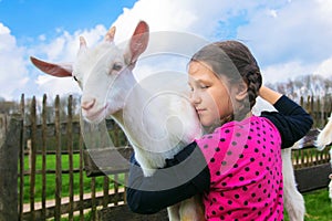 Little girl embracing a kid goat on a farm.
