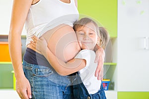 Little girl embracing pregnant mother