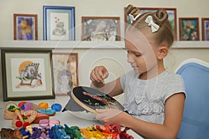 Little girl embroidering a bird on the black canvas