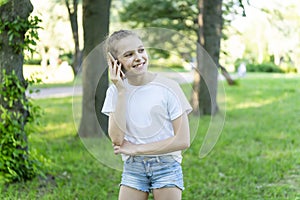 The little girl is emotionally talking on her cell phone. The park, the trees.