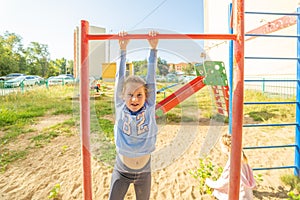 A little girl is engaged on a horizontal bar in the yard