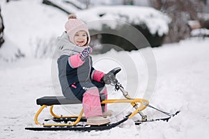 Little girl enjoy a sleigh ride. Kid sledding. Kids sled in park in winter. Outdoor fun for family Christmas vacation