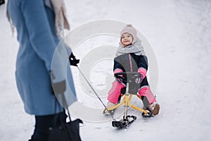 Little girl enjoying sledding. Mom sledding her little daughter. Family vacation on Christmas eve outdoors