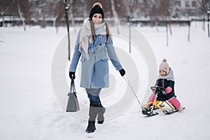 Little girl enjoying sledding. Mom sledding her little daughter. Family vacation on Christmas eve outdoors