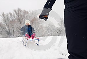 Little girl enjoying a sleigh ride. Child sledding. Toddler kid riding a sledge.