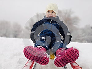 Little girl enjoying a sleigh ride. Child sledding. Toddler kid riding a sledge.