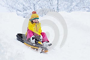 Little girl enjoying a sleigh ride. Child sledding. Toddler kid riding a sledge. Children play outdoors in snow. Kids sled in the