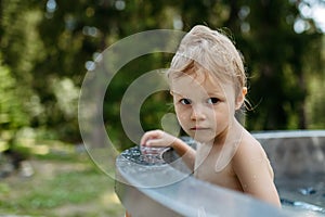 Little girl enjoying summer time in outdoor pool with his family, having fun.