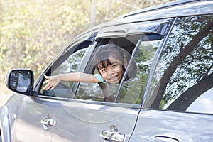 Little girl enjoying the trip smile and show hand out of car window.