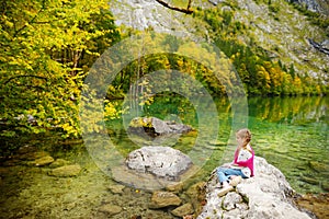 Little girl enjoying the view of deep green waters of Obersee, located near Konigssee, known as Germany`s deepest and cleanest la