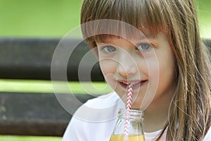 Little girl enjoys a beautiful and sunny day and drinking juice