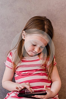 Little girl enthusiastically controls the phone. online learning games