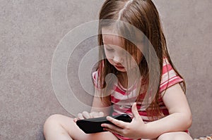 Little girl enthusiastically controls the phone. online learning games