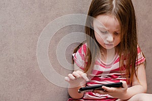 Little girl enthusiastically controls the phone. online learning games