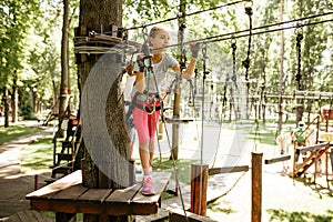 Little girl in equipment climbs in rope park