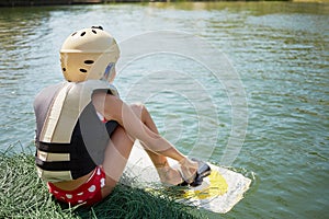 Little girl equipped for wakeboard sporting sits photo