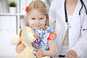 Little girl examining her Teddy bear by stethoscope. Health care, child-patient trust concept.