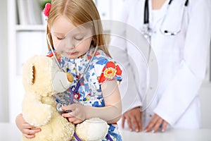 Little girl examining her Teddy bear by stethoscope. Health care, child-patient trust concept.