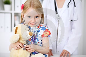 Little girl examining her Teddy bear by stethoscope. Health care, child-patient trust concept.