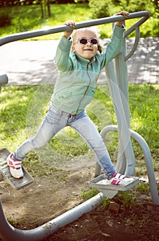 Little girl exercising on outdoor fitness machine