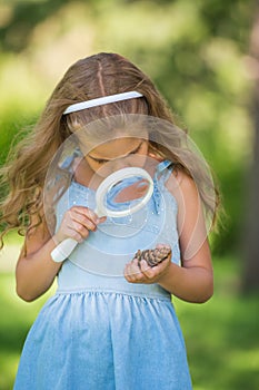 Little girl exploring the cone through the magnifying glass