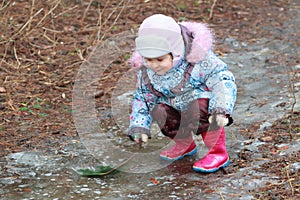 Little girl exploring icy puddle