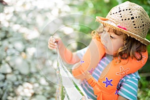 Little girl exploring map, alone in the forest or park