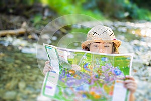 Little girl exploring map, alone in the forest or park