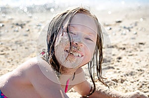 Little girl with face full of sand