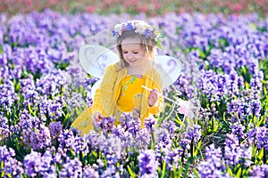 Little girl in fairy costume playing in flower field