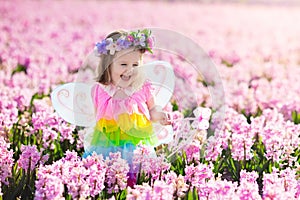 Little girl in fairy costume playing in flower field