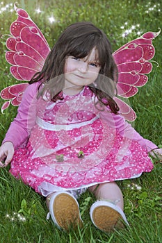 Little girl with fairy wings, pink dress and sparks of light