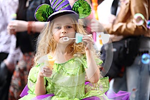 A little girl in fancy green dress blow soap bubbles