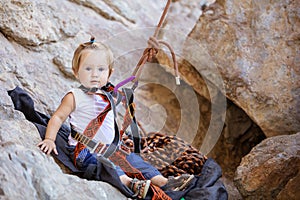 Little girl fastened to rock climbing gear